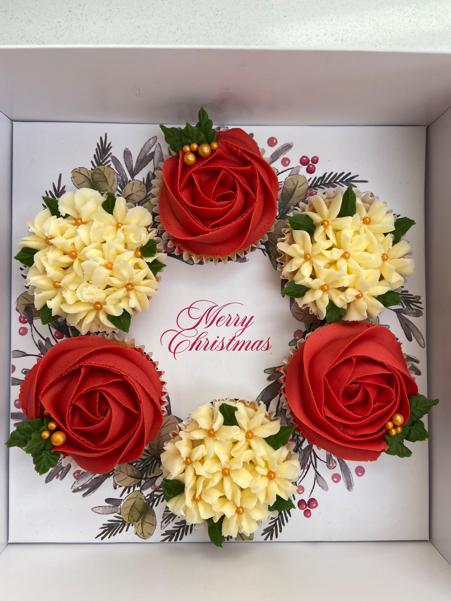 Classic Christmas Wreath boxed cupcake wreath with red poinsettia, cream rose, holly and pinecone buttercream arranged in a circle in a white gift box