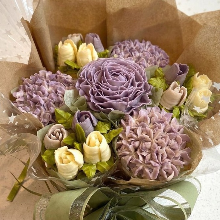 Sarah cupcake bouquet with lavender and cream buttercream flowers in kraft paper with a sage ribbon bow