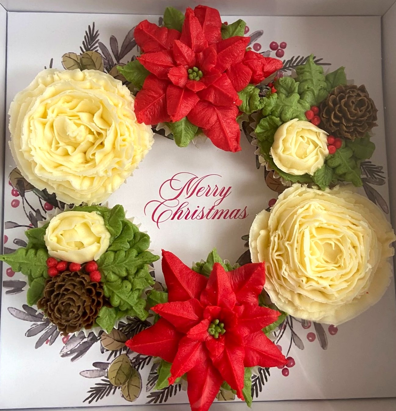 Christmas Wreath boxed cupcake wreath with red poinsettia, cream rose, holly and pinecone buttercream on a Merry Christmas card in a white gift box